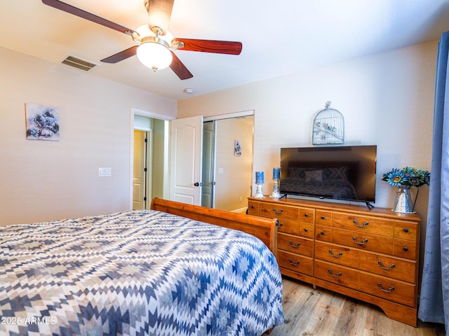 bedroom with a closet, wood finished floors, visible vents, and ceiling fan