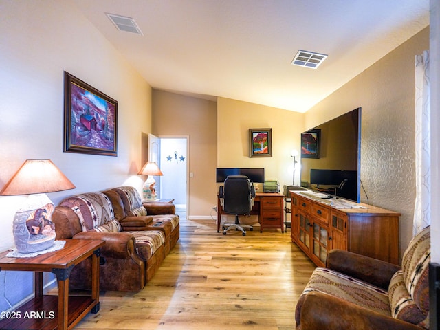 living area with lofted ceiling, baseboards, visible vents, and light wood-style floors