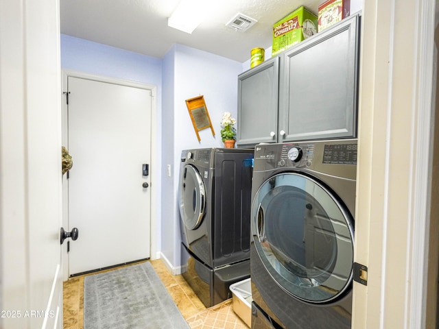 washroom with cabinet space, visible vents, light tile patterned floors, and washer and clothes dryer