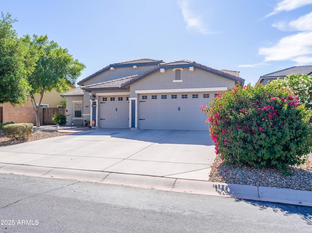 traditional-style home featuring fence, stucco siding, an attached garage, a tile roof, and driveway