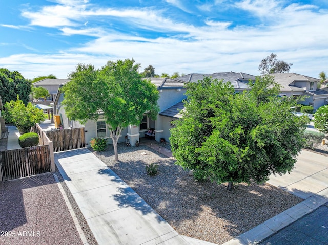 obstructed view of property featuring a gate, a fenced front yard, a tiled roof, stucco siding, and a residential view