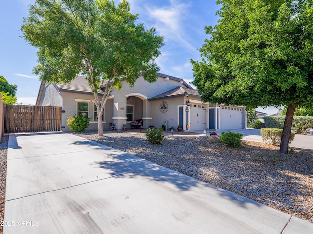 view of front facade featuring a gate, fence, stucco siding, concrete driveway, and a garage