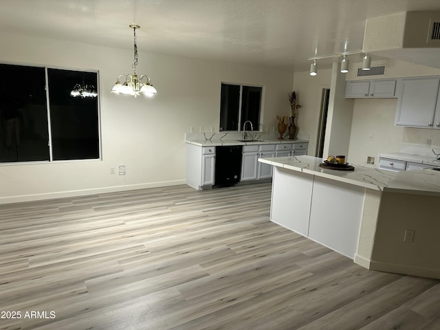 kitchen with decorative light fixtures, sink, black dishwasher, white cabinets, and light stone counters