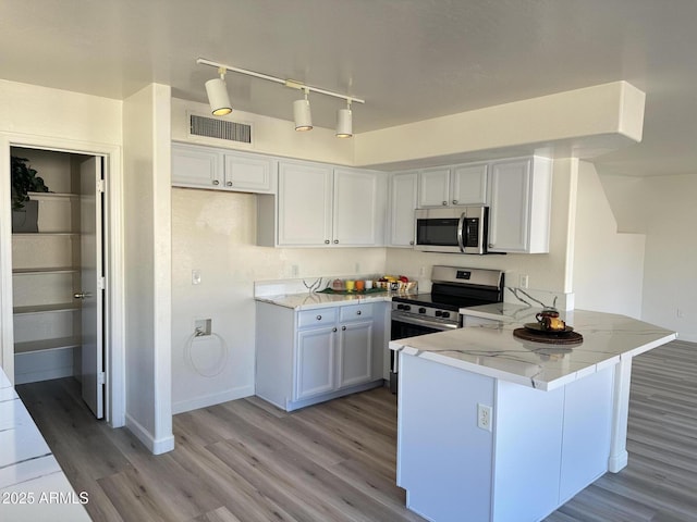 kitchen featuring white cabinets, kitchen peninsula, appliances with stainless steel finishes, and light stone counters