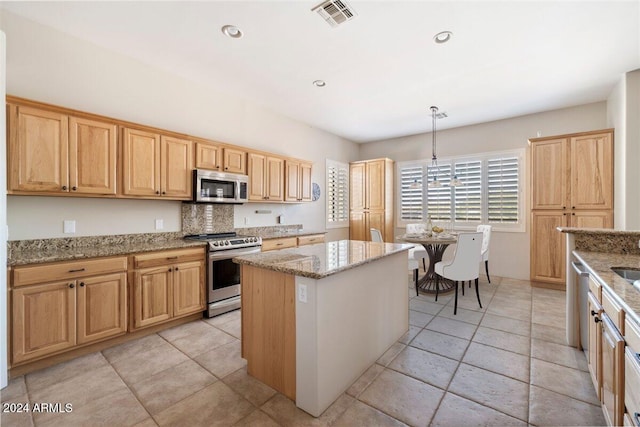 kitchen featuring appliances with stainless steel finishes, light stone counters, hanging light fixtures, and a kitchen island