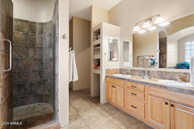 bathroom with a shower with door, vanity, and tile patterned flooring