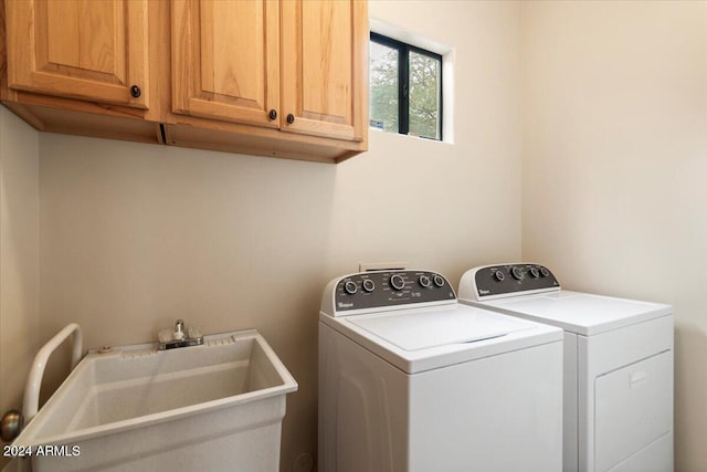 clothes washing area with sink, washing machine and clothes dryer, and cabinets