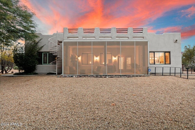 back house at dusk with a sunroom