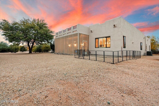 14428 E Monument Dr, Scottsdale, AZ 85262 - back of property at dusk featuring a sunroom, fence, and stucco siding