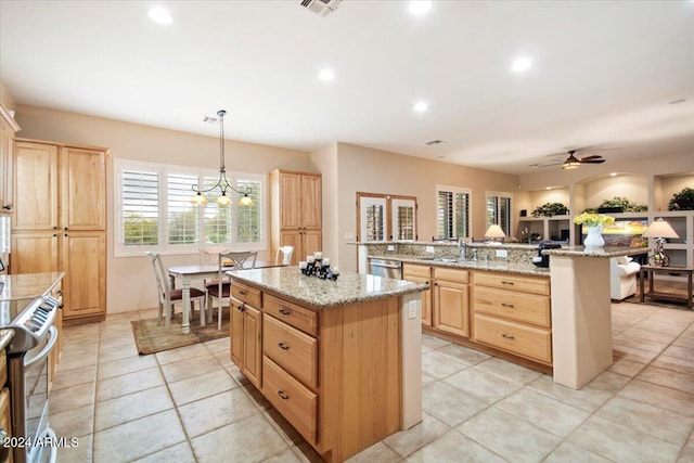 kitchen featuring light brown cabinets, a kitchen island, sink, ceiling fan with notable chandelier, and decorative light fixtures