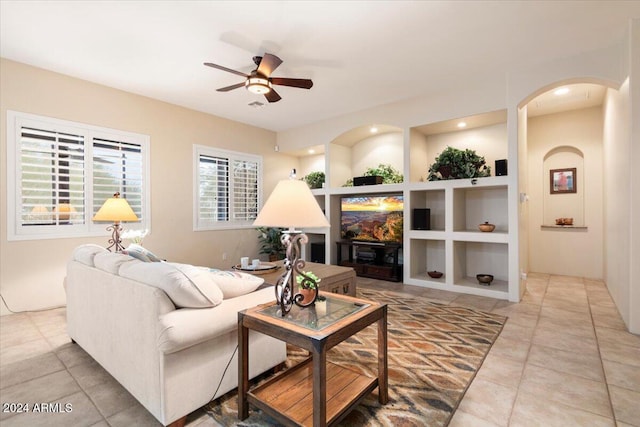 living room featuring ceiling fan, built in features, and tile patterned flooring