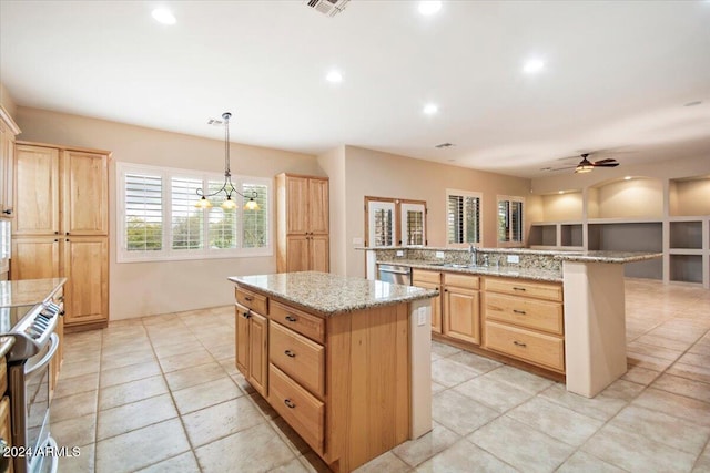 kitchen featuring kitchen peninsula, a kitchen island, sink, ceiling fan with notable chandelier, and decorative light fixtures