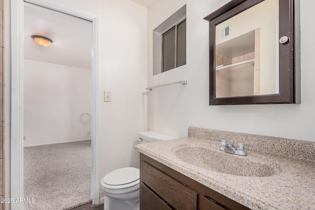bathroom featuring toilet, vanity, and an enclosed shower