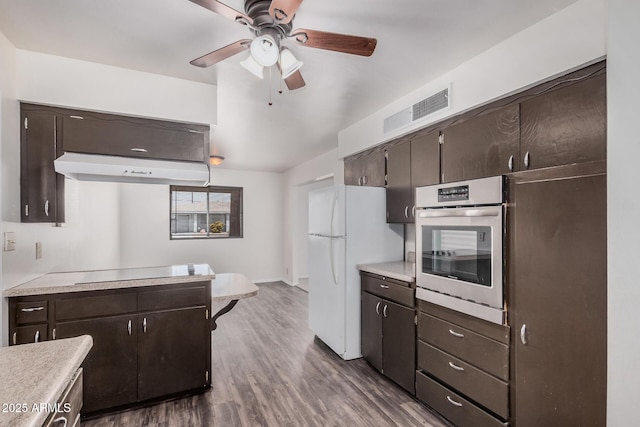 kitchen featuring stainless steel oven, freestanding refrigerator, under cabinet range hood, and dark brown cabinets