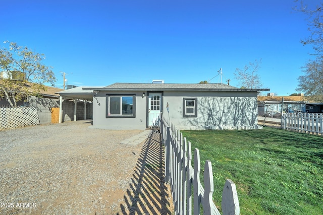 back of property with a carport and a lawn