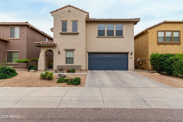 mediterranean / spanish home with a tiled roof, an attached garage, concrete driveway, and stucco siding
