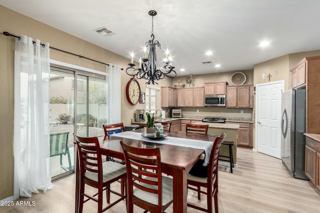dining area with light wood finished floors, visible vents, recessed lighting, and a notable chandelier