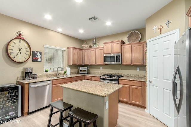 kitchen featuring a sink, light wood finished floors, appliances with stainless steel finishes, wine cooler, and visible vents