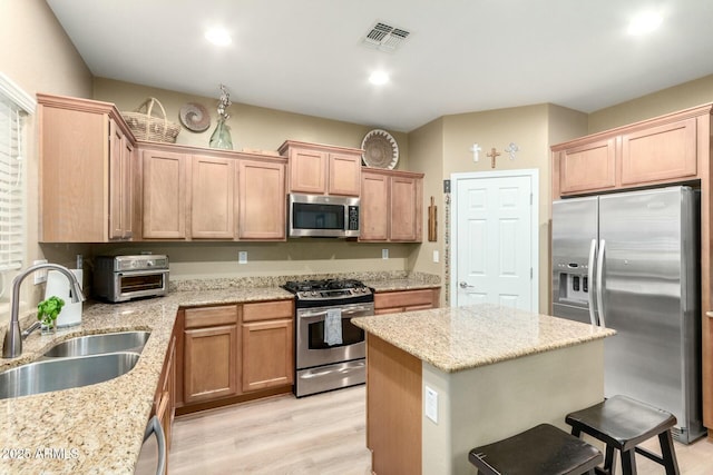 kitchen with visible vents, a sink, a center island, appliances with stainless steel finishes, and a breakfast bar area