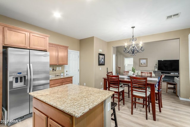 kitchen featuring light wood-type flooring, visible vents, an inviting chandelier, stainless steel fridge with ice dispenser, and a kitchen island