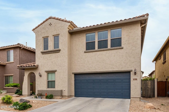 view of front of property featuring fence, a tiled roof, stucco siding, an attached garage, and driveway