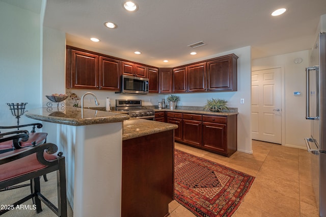 19700 N 76th St Unit 2001, Scottsdale, AZ 85255 - kitchen featuring a peninsula, dark stone countertops, stainless steel appliances, visible vents, and recessed lighting