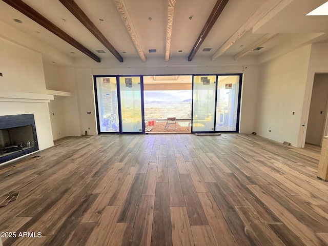 unfurnished living room with beamed ceiling, visible vents, wood finished floors, and a fireplace