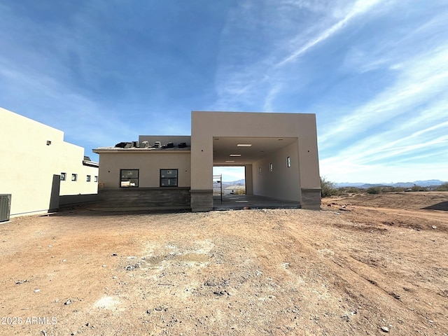 rear view of house featuring stucco siding and central AC