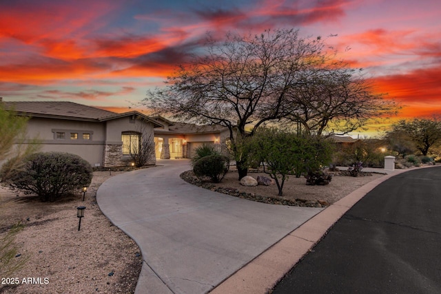 view of front of property featuring stucco siding, stone siding, and curved driveway