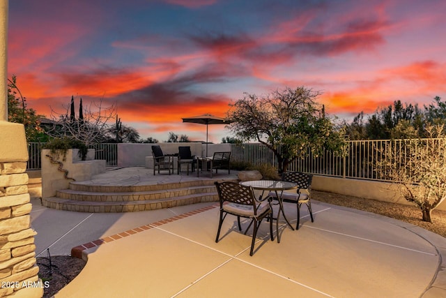 patio terrace at dusk featuring fence