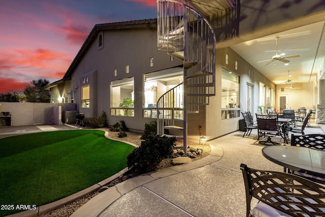 back of property at dusk with stucco siding, a patio, and ceiling fan