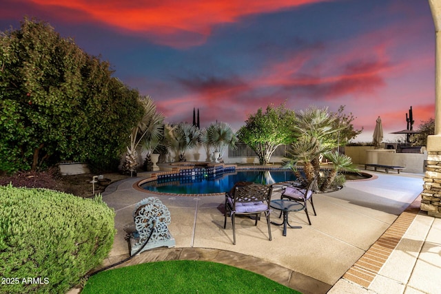 pool at dusk featuring a patio area and a fenced in pool