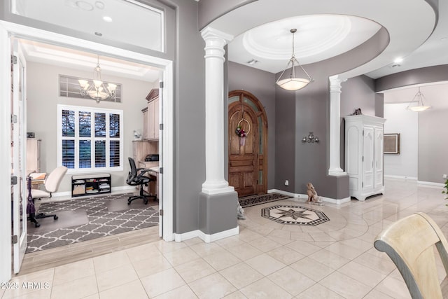 foyer entrance with an inviting chandelier, a raised ceiling, arched walkways, and ornate columns