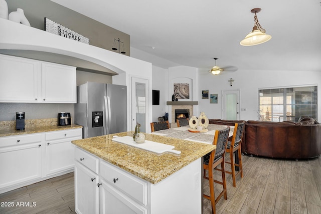 10226 W Country Club Trl, Peoria, AZ 85383 - kitchen featuring stainless steel refrigerator with ice dispenser, open floor plan, light wood finished floors, a warm lit fireplace, and a ceiling fan