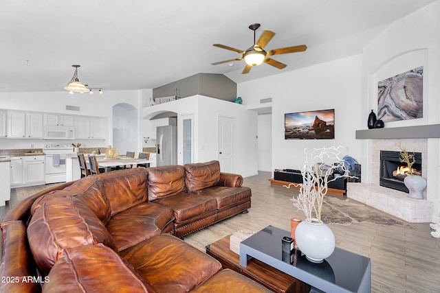 10226 W Country Club Trl, Peoria, AZ 85383 - living room with a ceiling fan, vaulted ceiling, arched walkways, a fireplace, and light wood-style flooring