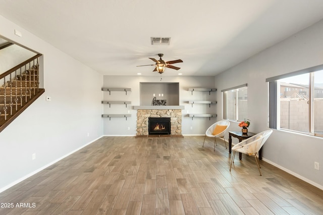 unfurnished room with a stone fireplace and ceiling fan