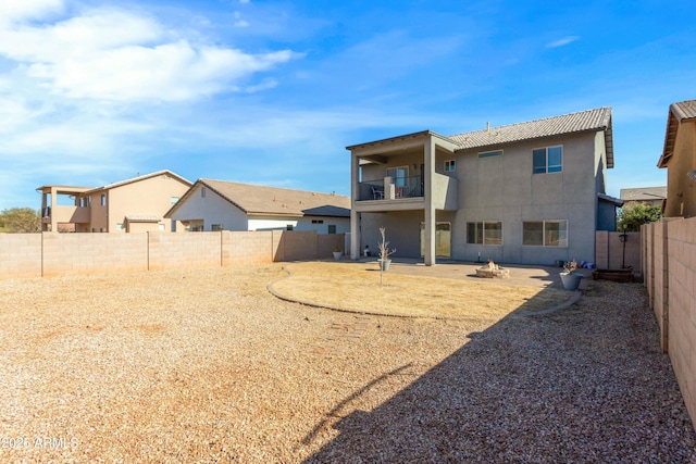 back of property with a patio, a balcony, and a fire pit