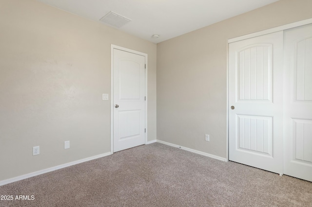 unfurnished bedroom featuring light colored carpet and a closet