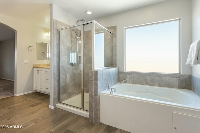 bathroom with vanity, wood-type flooring, and plus walk in shower