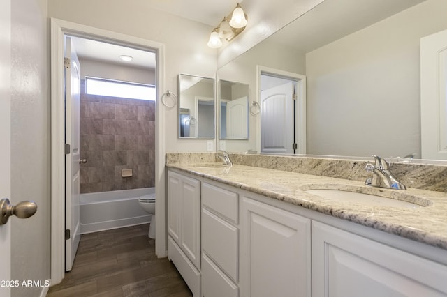 full bathroom featuring hardwood / wood-style flooring, vanity, toilet, and tiled shower / bath