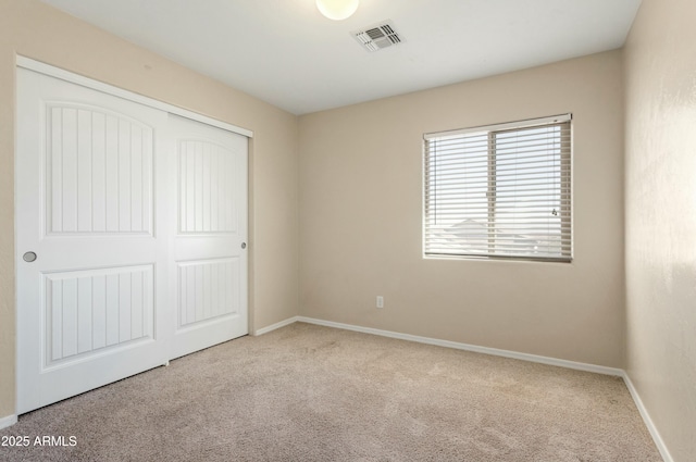 unfurnished bedroom featuring light colored carpet and a closet