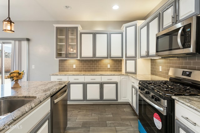 kitchen with light stone countertops, appliances with stainless steel finishes, white cabinets, and decorative light fixtures