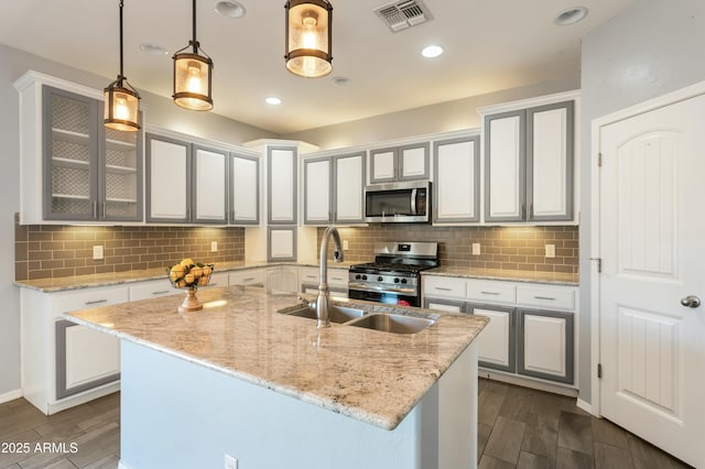 kitchen with pendant lighting, white cabinetry, sink, a kitchen island with sink, and stainless steel appliances