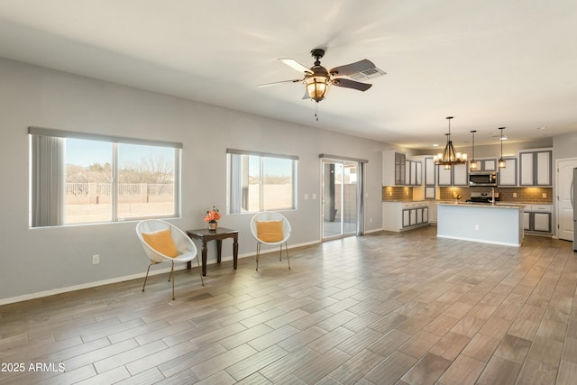 unfurnished living room featuring ceiling fan with notable chandelier