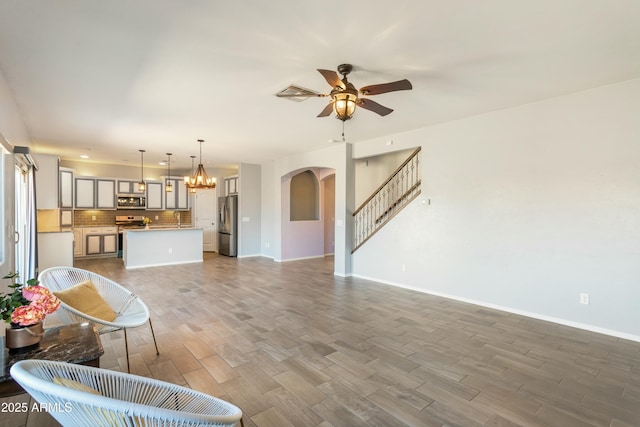 living room featuring hardwood / wood-style floors, ceiling fan with notable chandelier, and sink