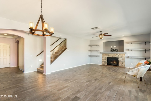 unfurnished living room with ceiling fan with notable chandelier, hardwood / wood-style floors, and a fireplace