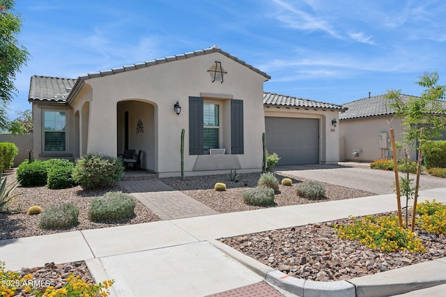 mediterranean / spanish-style home with a garage, a tiled roof, and stucco siding