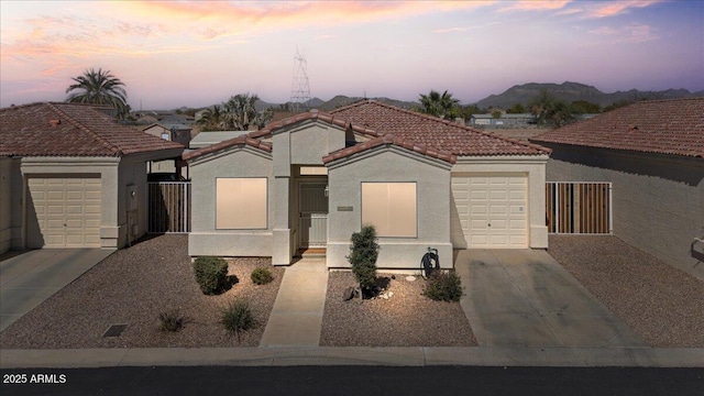 view of front of house featuring an attached garage, a mountain view, a tile roof, driveway, and stucco siding