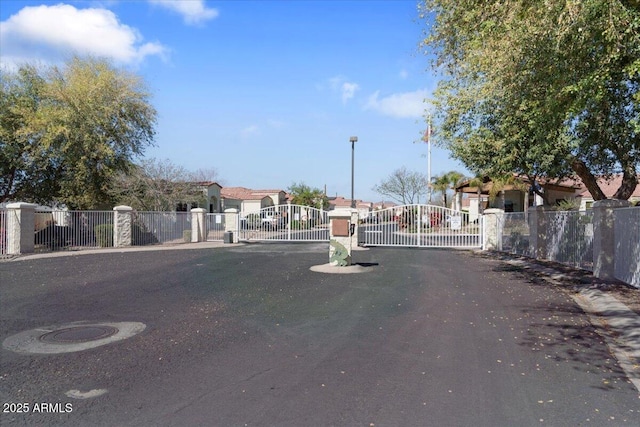 view of street with street lights, a gate, a gated entry, a residential view, and curbs