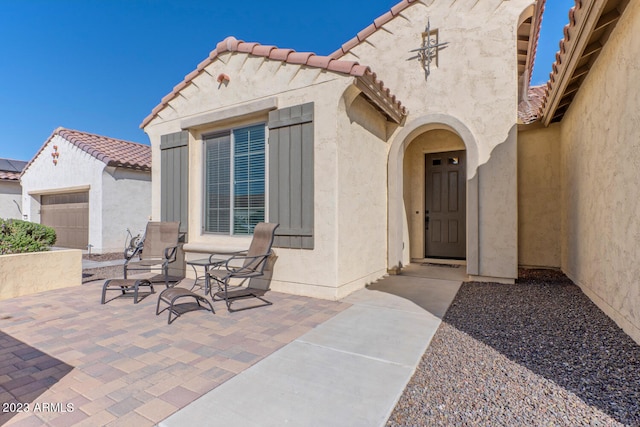 view of exterior entry featuring a patio and a garage